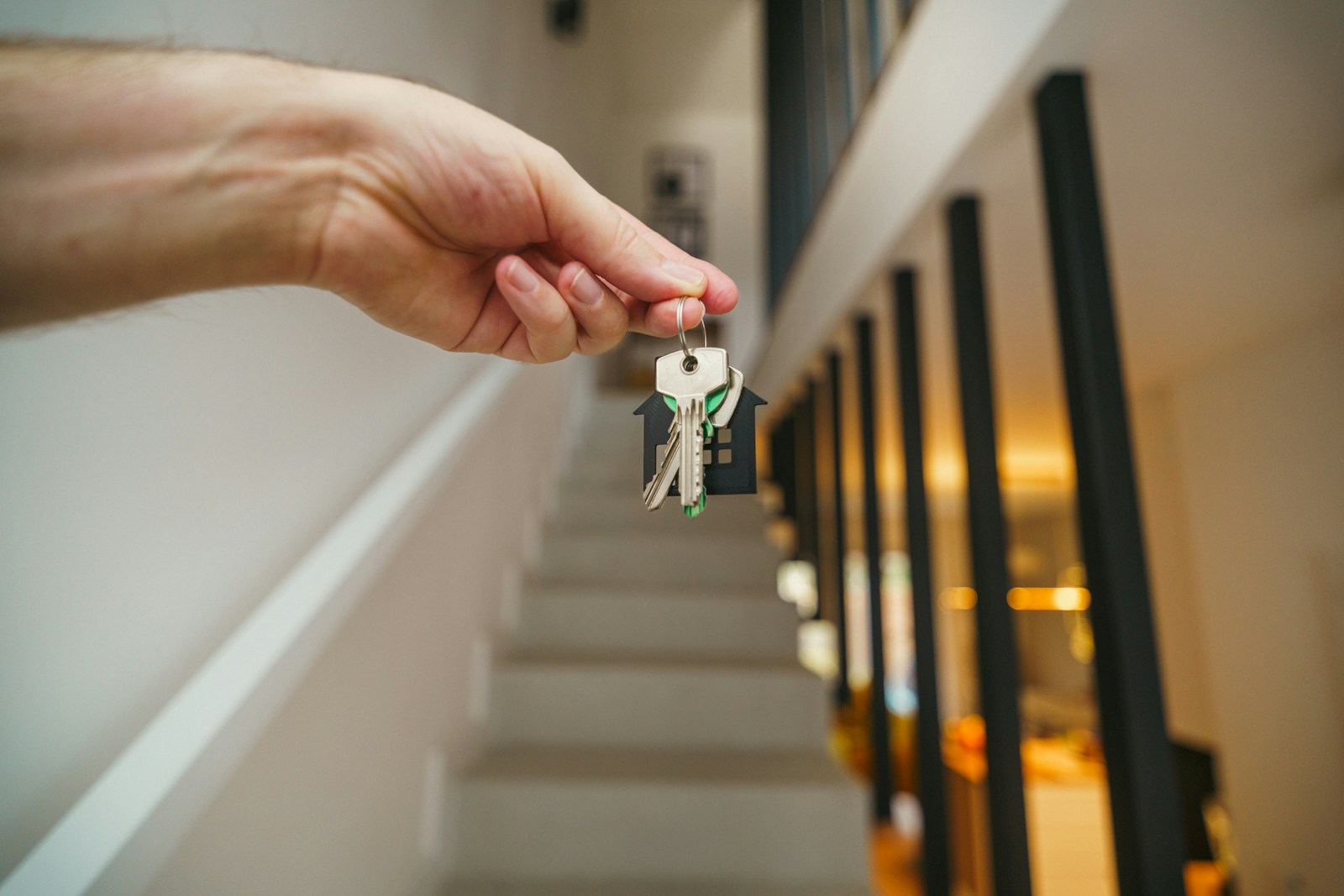 Here's a possible caption: keys being held in front of a staircase, landlord, renters