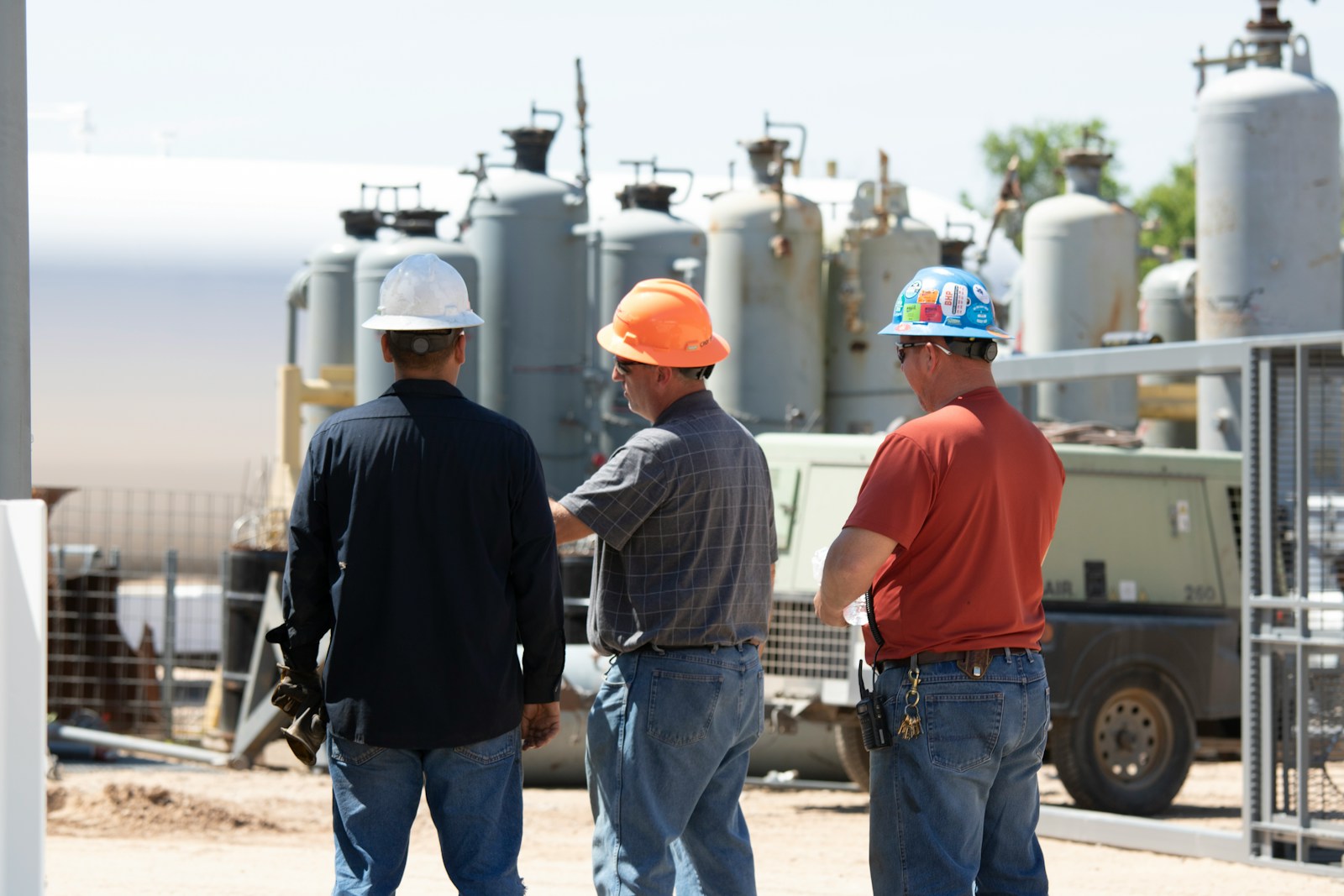 man in black jacket standing beside man in orange shirt, contractors